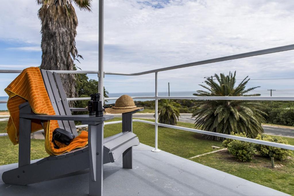 吉爾德頓的住宿－Seascape - Outstanding Views Pet Friendly Free WIFI Netflix，坐在阳台上长凳上的帽子