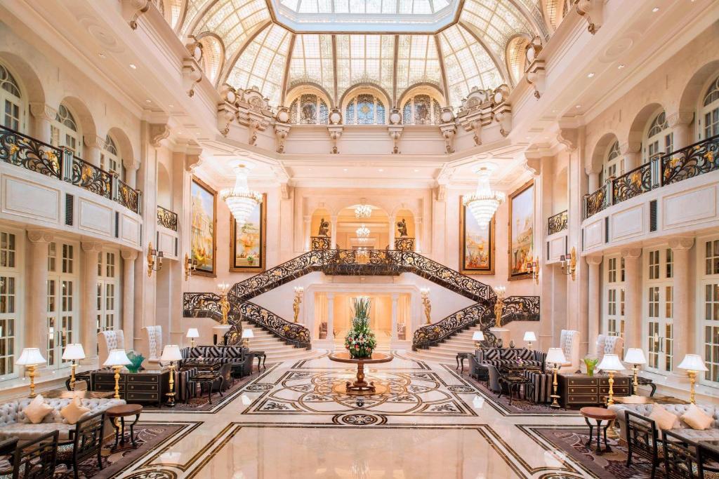 un vestíbulo con una escalera de caracol, mesas y sillas en The Castle Hotel, a Luxury Collection Hotel, Dalian en Dalian