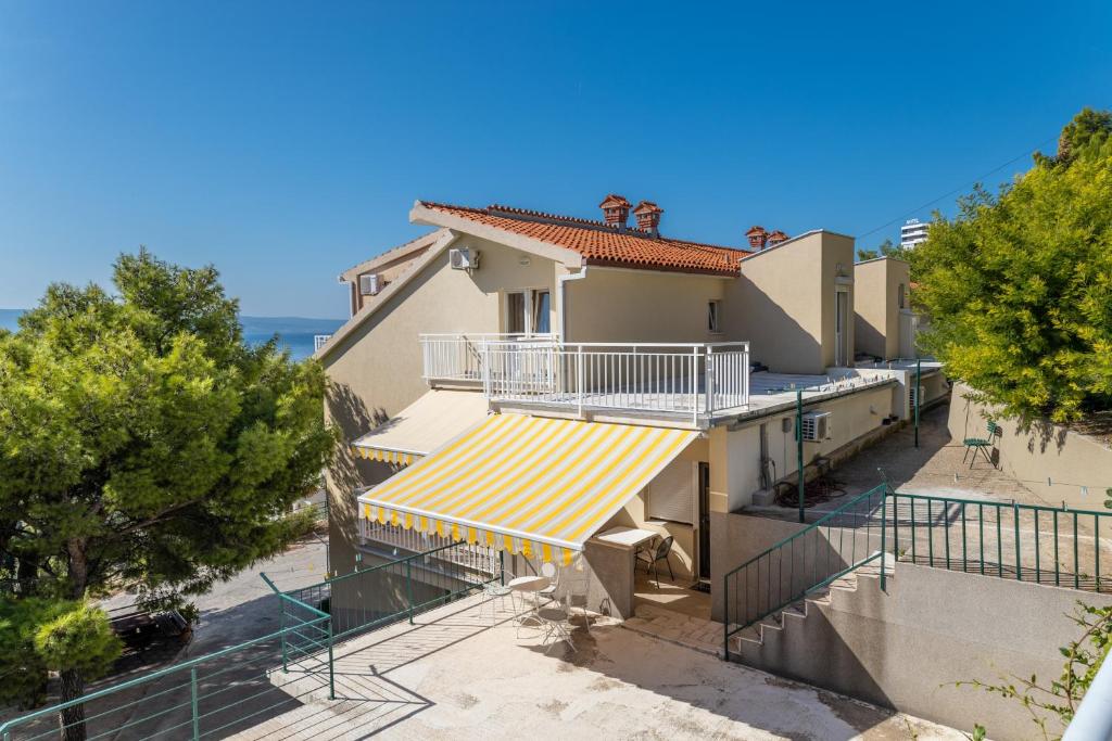 a house with a balcony with a yellow and white awning at Apartments by the sea Duce, Omis - 946 in Duće