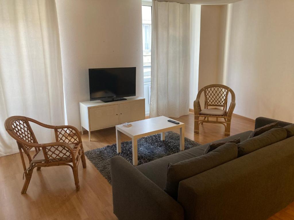 - un salon avec un canapé, des chaises et une télévision dans l'établissement Ravissant Appartement T3 hypercentre de Mazamet, à Mazamet