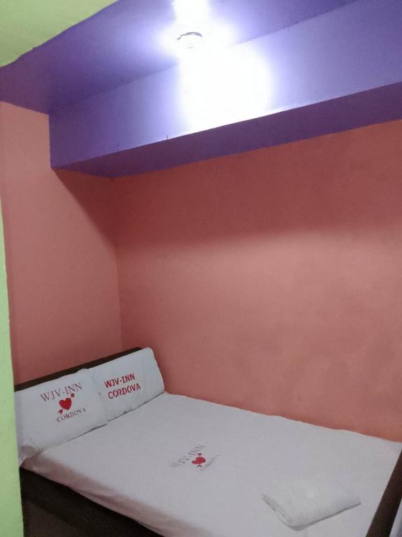 Kleines Zimmer mit einem Bett und einer Decke in der Unterkunft WJV INN Cordova in Cebu City