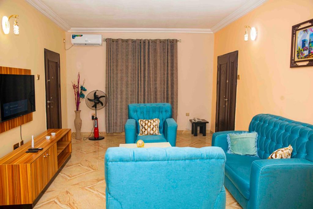 sala de estar con sillas azules y TV de pantalla plana en Cogent Apartments en Uyo