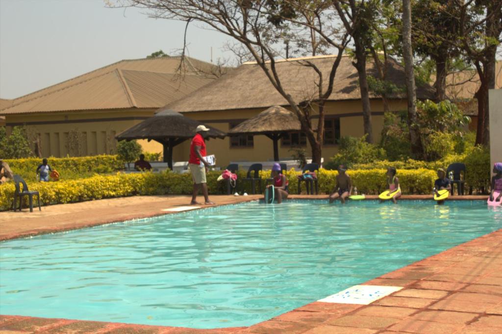 a group of people standing around a swimming pool at Demera Motel in Lilongwe