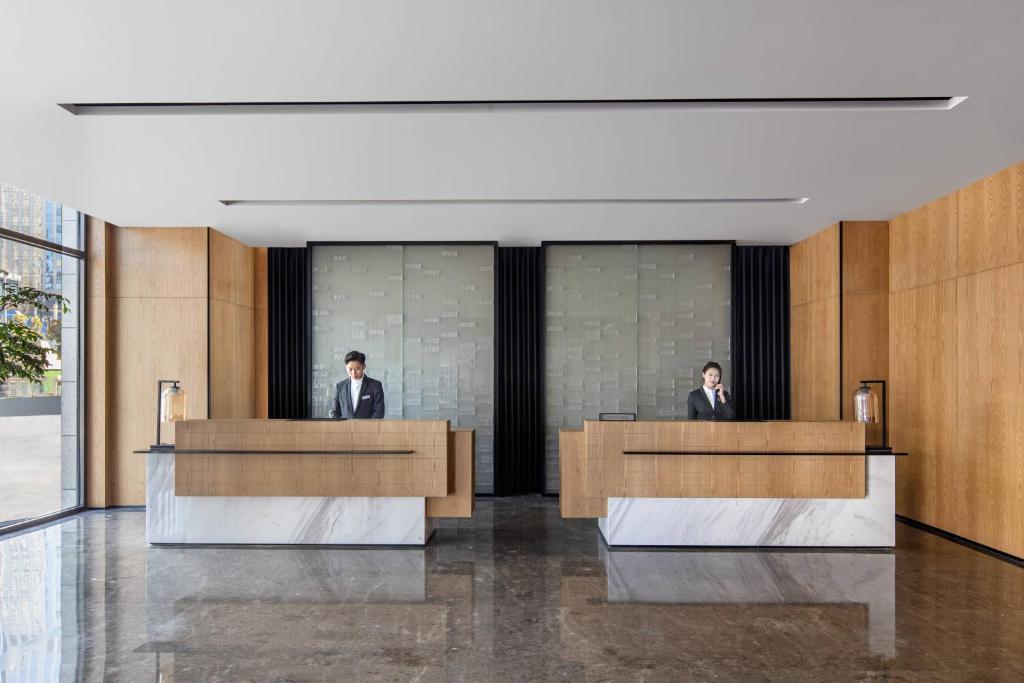 two men are sitting at desks in a lobby at Fairfield by Marriott Guiyang Guanshanhu in Guiyang