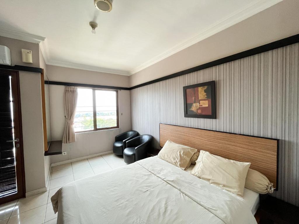ein Schlafzimmer mit einem Bett, einem Stuhl und einem Fenster in der Unterkunft Studio at Grand Setiabudi Apartment in Bandung