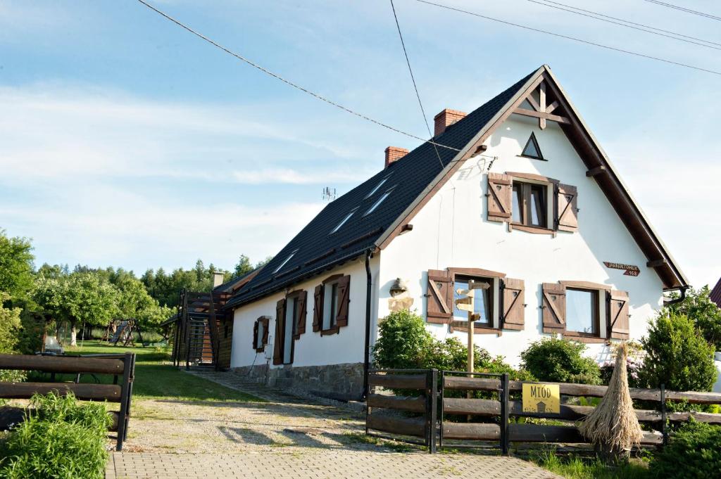 une maison blanche avec un toit noir dans l'établissement Włóczykijówka, à Jarnołtówek