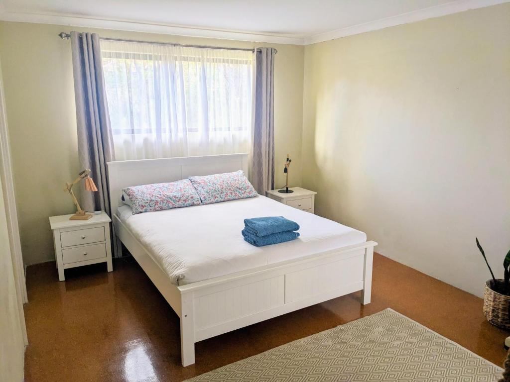 ein weißes Bett in einem Zimmer mit Fenster in der Unterkunft Bright & breezy chalet close to town & beach in Dunsborough