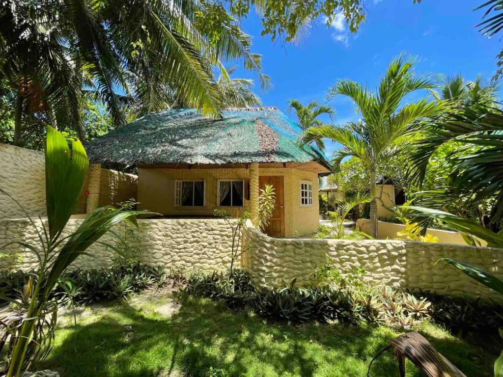 mały dom z płotem przed nim w obiekcie Victory Seaside Home w mieście Wyspa Bantayan