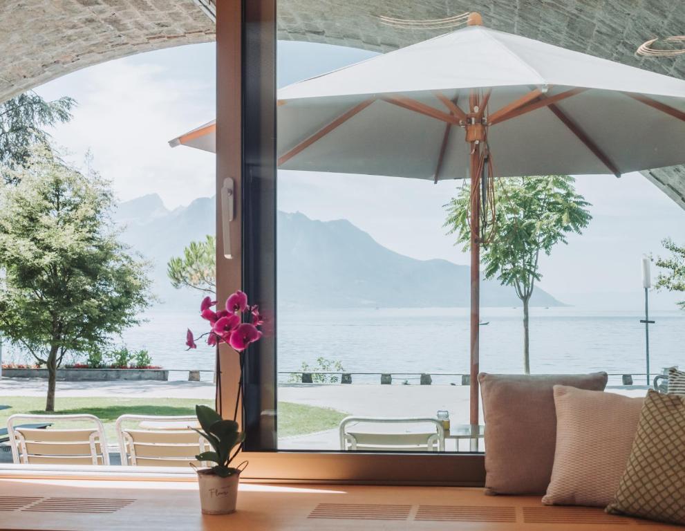 een patio met een parasol en uitzicht op het water bij Montreux Youth Hostel in Montreux