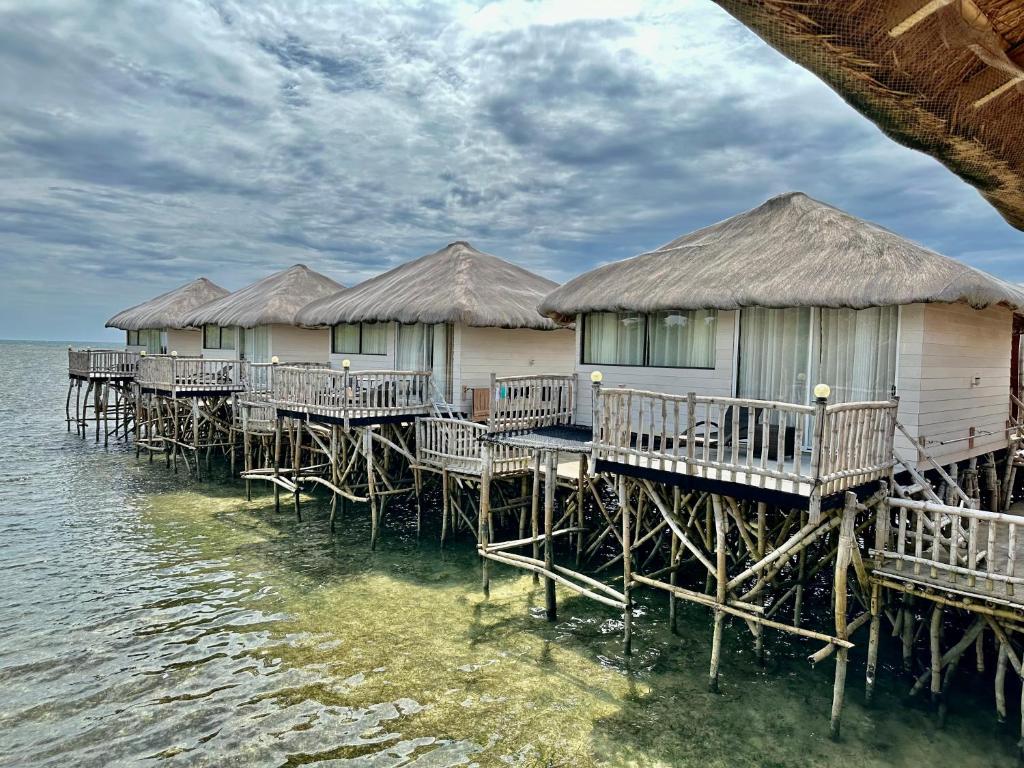 a row of huts on the water in the ocean w obiekcie Kaway Resort & Spa w mieście Tabuelan