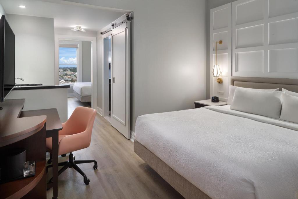 um quarto de hotel com uma cama branca e uma secretária. em Courtyard by Marriott New Orleans French Quarter/Iberville em Nova Orleans