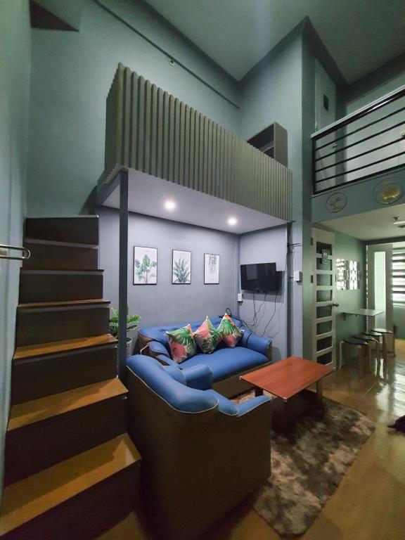 - un salon avec un canapé bleu et un escalier dans l'établissement Cozy Lofts closed to Shopping Malls & MRT Station, à Manille
