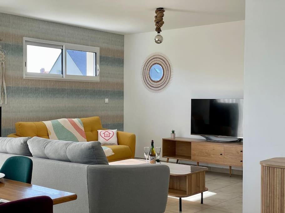 uma sala de estar com um sofá e uma televisão em Refuge côté Mer by Melrose em Asnelles