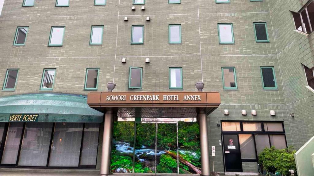 Aomori Green Park Hotel Annex في أوموري: مبنى من الطوب كبير مع علامة أمامه