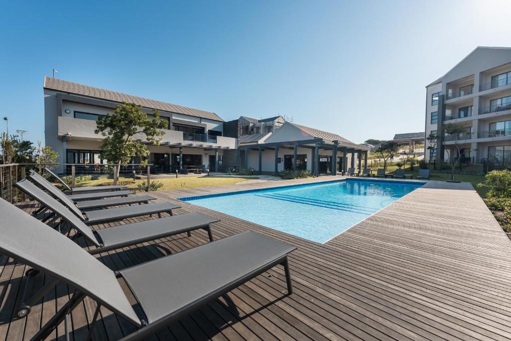 a swimming pool with chaise lounge chairs next to a building at 159 Ballito Village 2 Bedroom Unit in Ballito