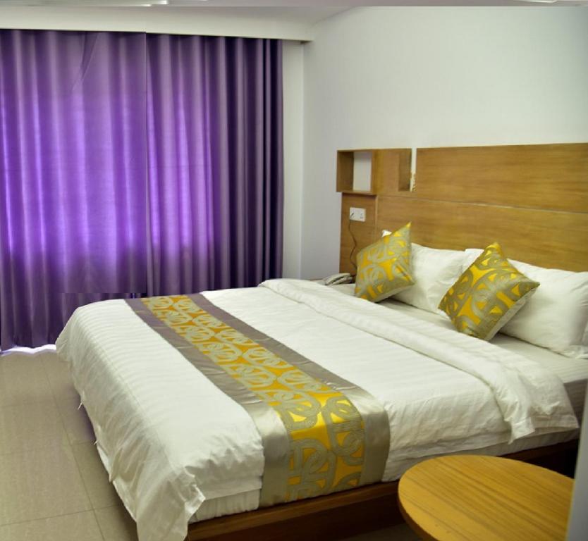 a bedroom with a large bed with purple curtains at Annex Suites Bogra - CityCentre in Bogra