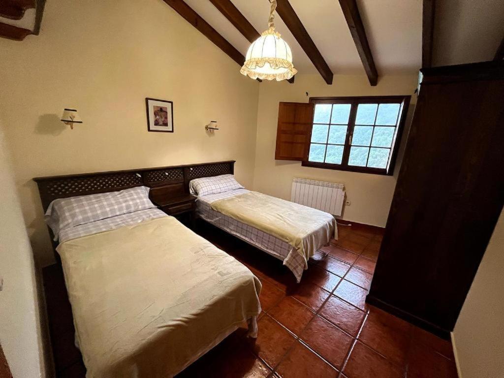 una camera con due letti e un lampadario a braccio di Casa G. Mirador de las Ubiñas a Ríospaso