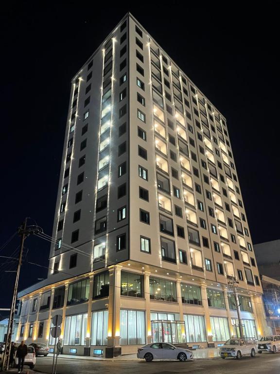 a tall building with two cars parked in front of it at MyFlower 3 Hotel in Erbil