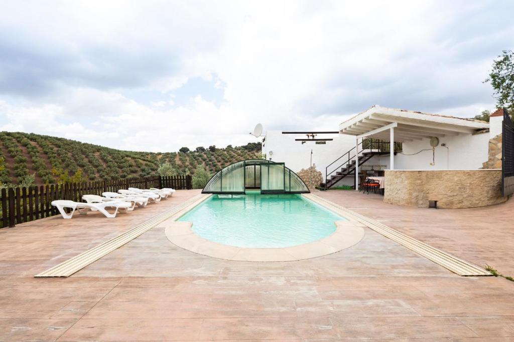 a swimming pool on a patio with chairs and a building at La Pedriza del Serval in Montefrío