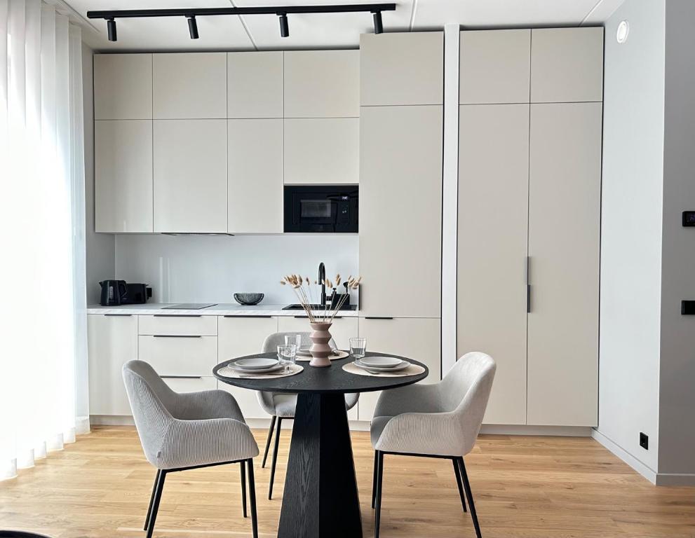 パルヌにあるEsplanaadi Residencesの白いキャビネット、テーブルと椅子付きのキッチンが備わります。