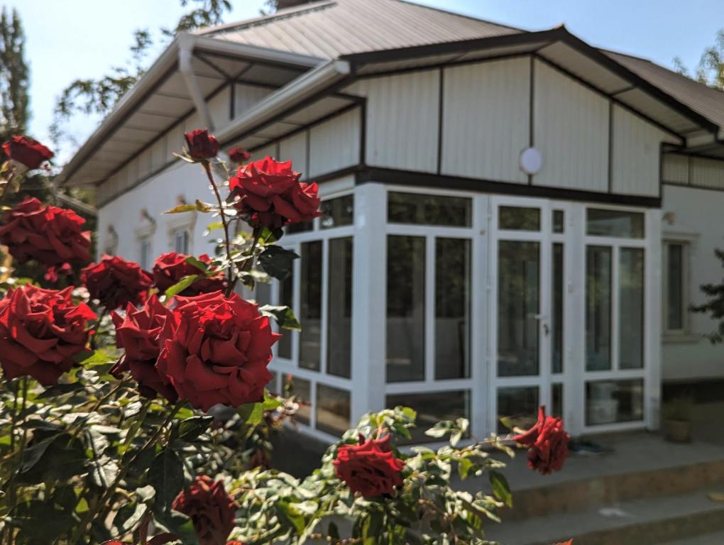 Uma casa com rosas vermelhas à frente. em Rice House Near Uzgen 