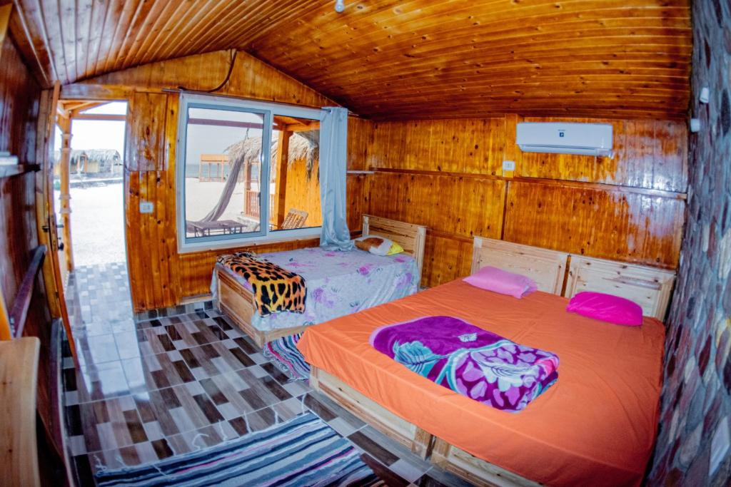 a bedroom with two beds in a wooden cabin at Yasmina Beach in Taba