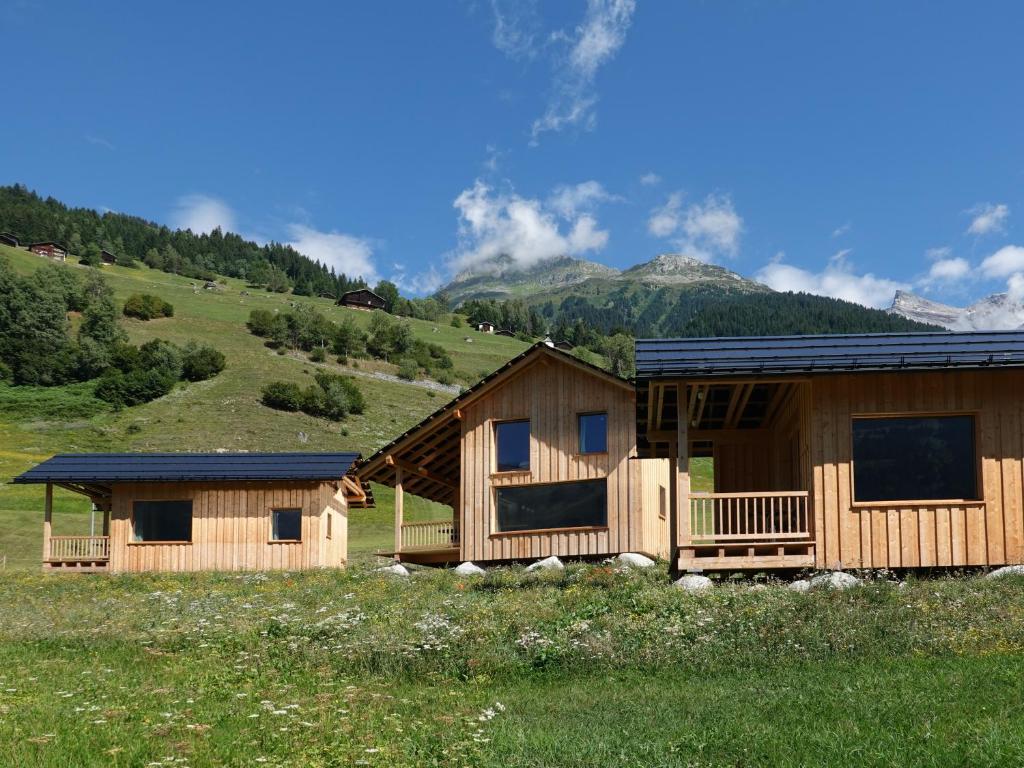 een hut in een veld met bergen op de achtergrond bij Ferienhäuser Stiva Pintga 