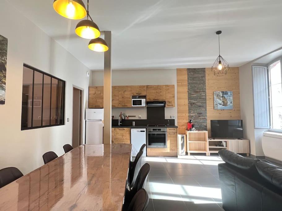 Il comprend une cuisine et un salon avec une grande table en bois. dans l'établissement Joli T3 rénové ds une villa 1900, à Cauterets