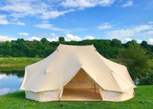 a white tent sitting on the grass next to a lake at Silverstone Farm Campsite in Silverstone