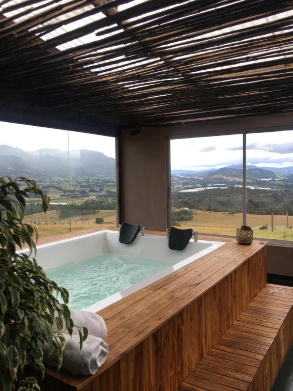 a bath tub in a room with a large window at Hotel Ika Mirador Suesca in Suesca