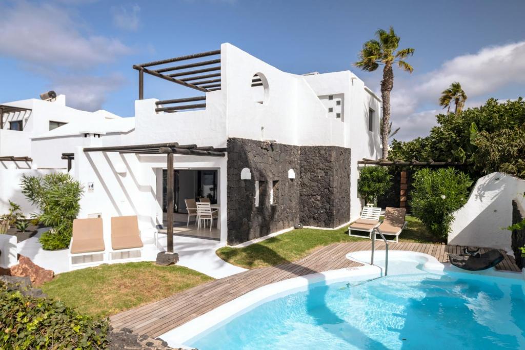 a villa with a swimming pool and a house at Kamezí Boutique Hotel Villas in Playa Blanca