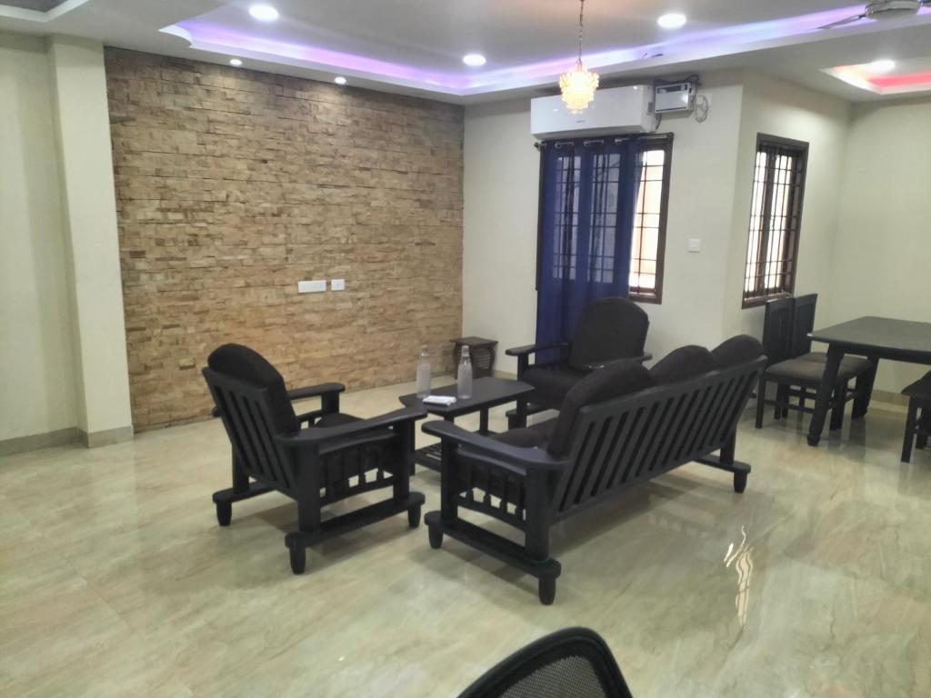 a waiting room with black chairs and tables and a brick wall at vinoth in Mannārgudi
