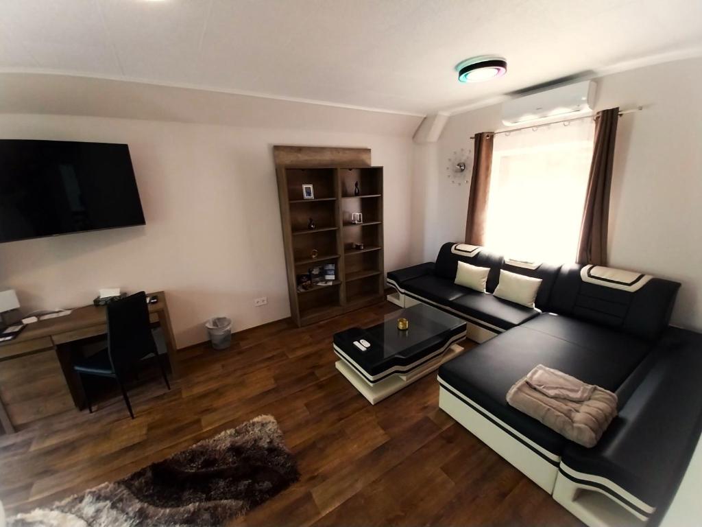 a living room with a black couch and a desk at HUNOR Vendégház in Sátoraljaújhely
