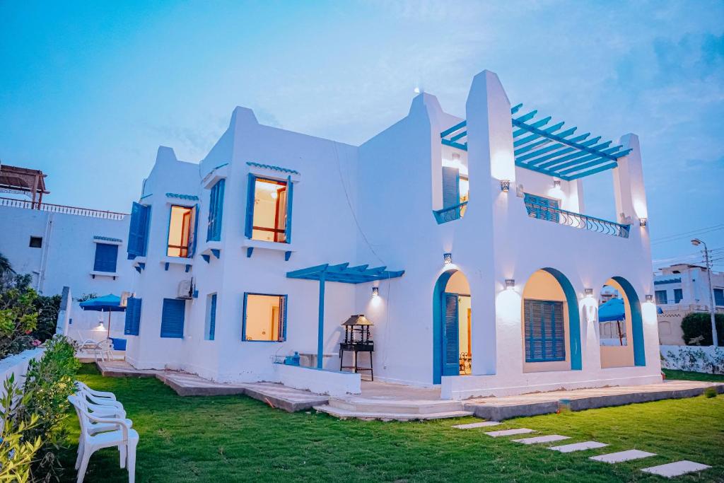 uma casa branca com um relvado à frente em 4 bedrooms villa with private pool in Tunis village faiuym em Qaryat at Ta‘mīr as Siyāḩīyah
