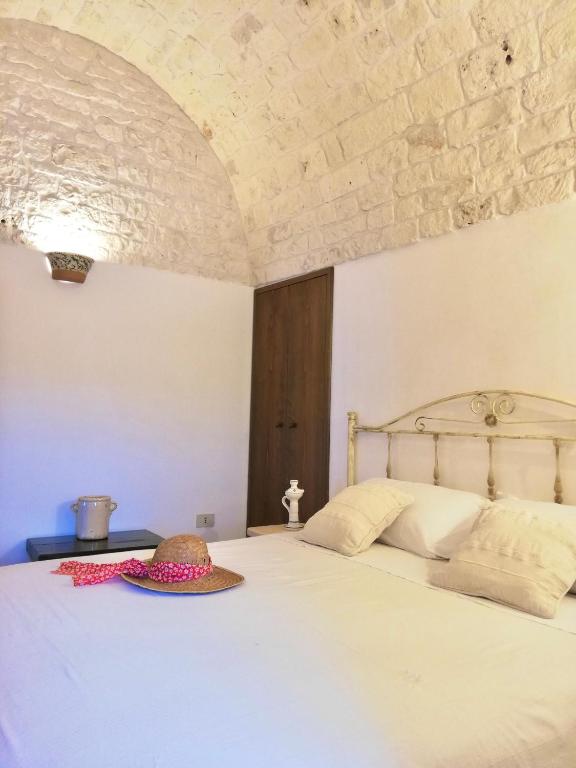 sypialnia z białym łóżkiem i kamienną ścianą w obiekcie Trulli Bosco Selva w Alberobello