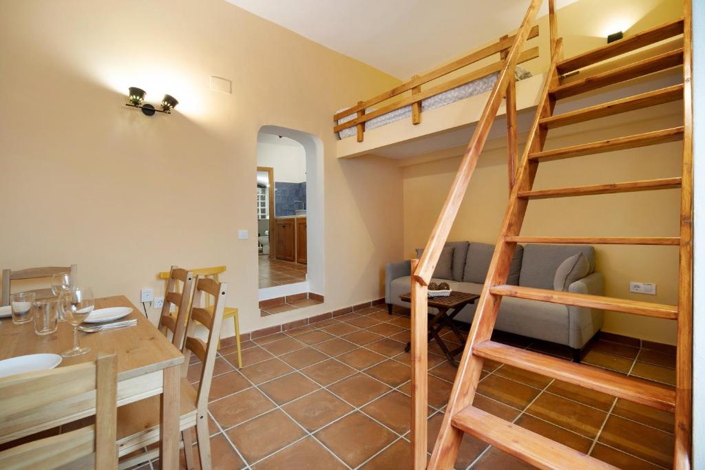 a dining room and living room with a loft bed at Apartamento-cueva Mi Rincón in Arcos de la Frontera