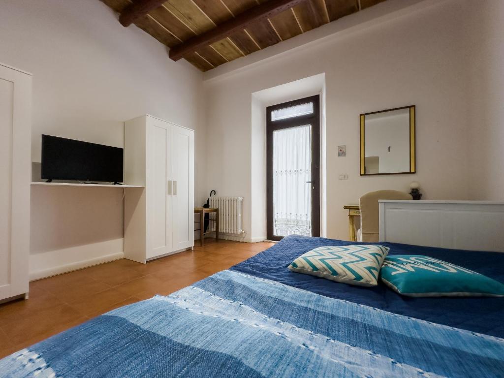 Cette chambre comprend un lit avec des draps bleus et une télévision. dans l'établissement Host4All casa vacanze, à Falconara Marittima