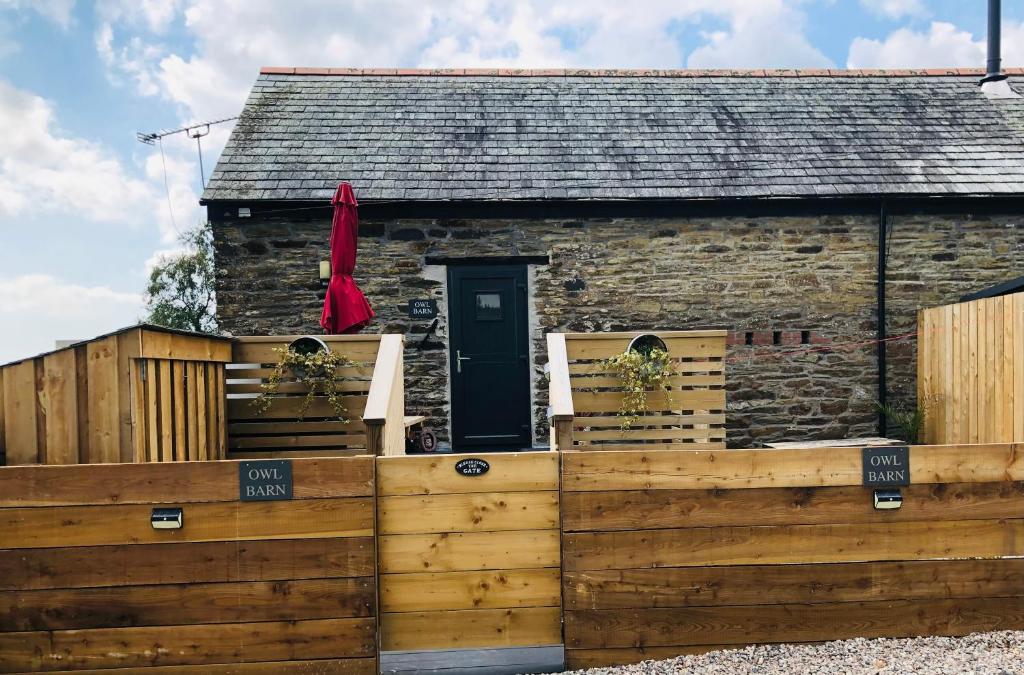 une maison avec une clôture en bois devant elle dans l'établissement Owl Barn, à Liskeard