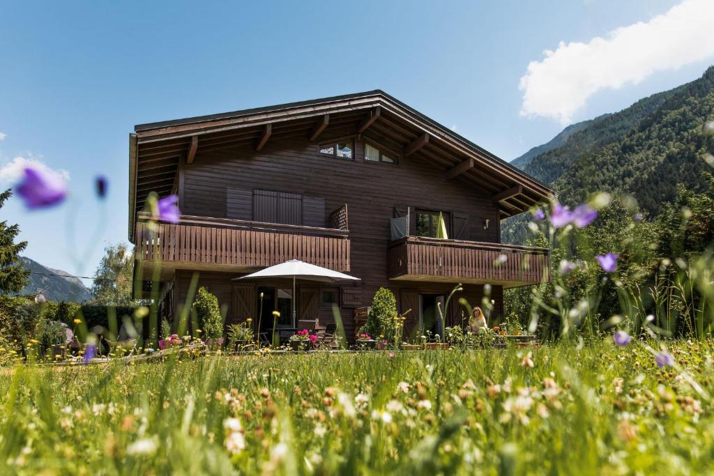a wooden house with a balcony in a field of flowers at Apartment Cry - Alpes Travel - Central Chamonix (sleeps 2-4) in Chamonix-Mont-Blanc