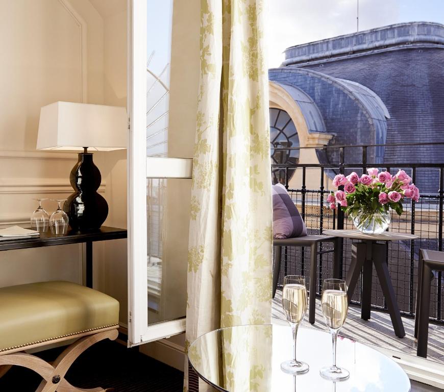 a room with a table with wine glasses on a balcony at Grand Hôtel Du Palais Royal in Paris