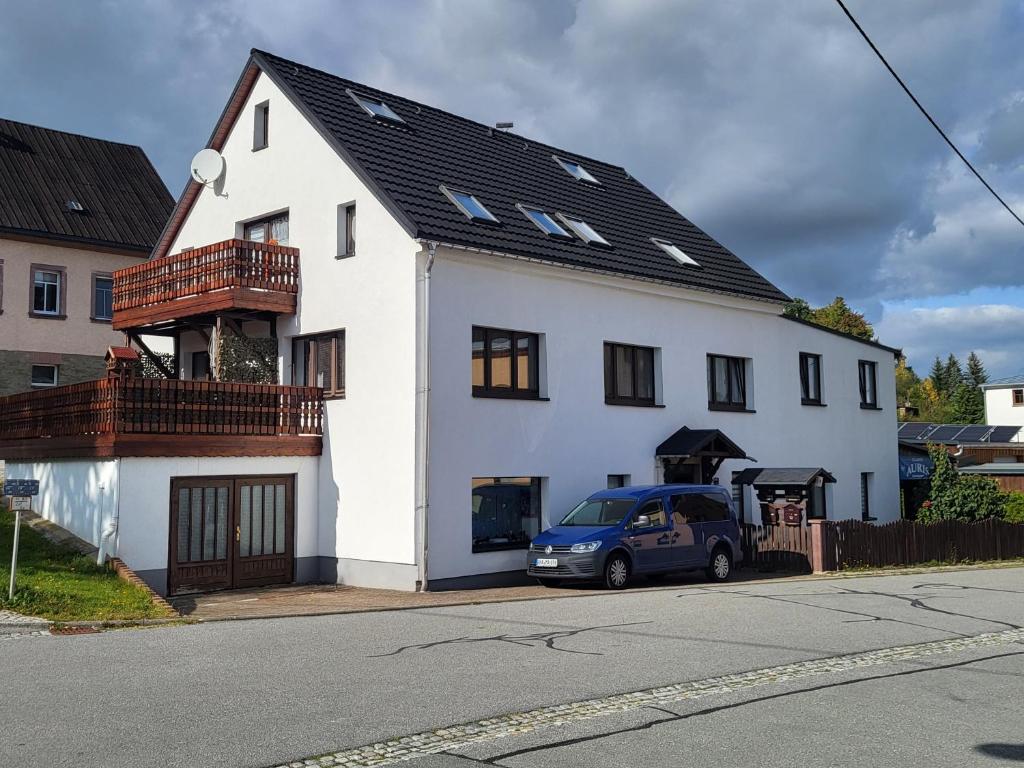 ein weißes Haus mit einem davor geparkt in der Unterkunft Ferienwohnung Auris in Cranzahl