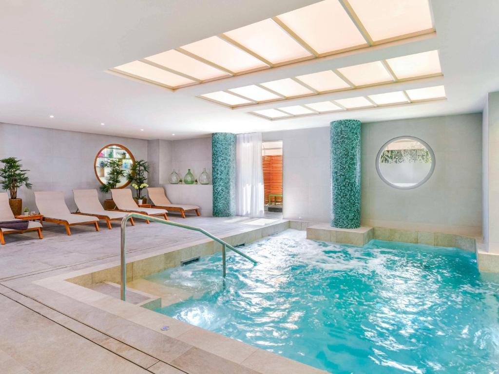 a pool in a room with chairs and a table at Pullman La Pléiade Montpellier Centre in Montpellier