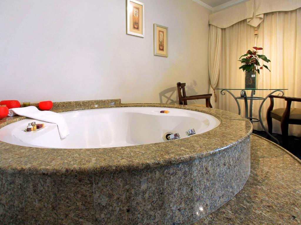 a bathroom with a large tub in a room at Mercure Jaragua do Sul in Jaraguá do Sul