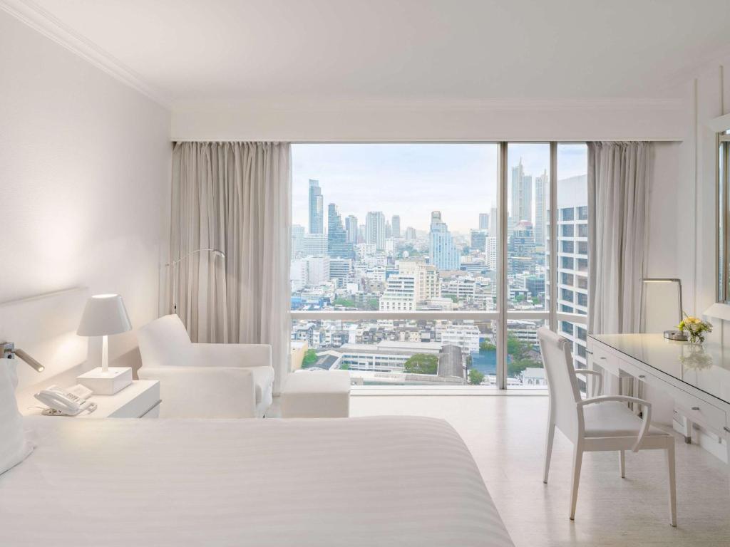 a white hotel room with a view of a city at Pullman Bangkok Hotel G in Bangkok