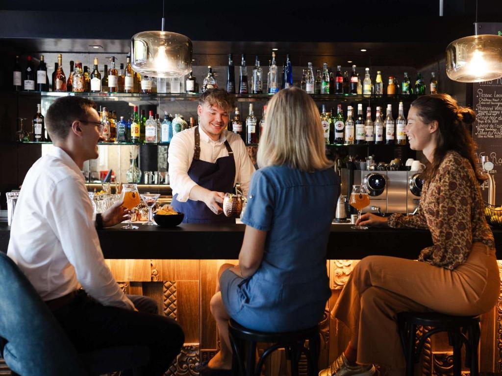 a group of people sitting at a bar at Mercure Valenciennes Centre in Valenciennes