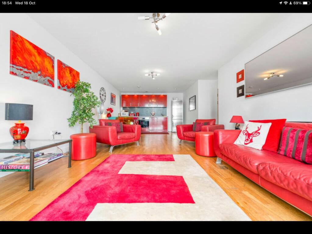 a living room with red furniture and a red rug at Stunning Spacious City Apartment with free parking in Cardiff