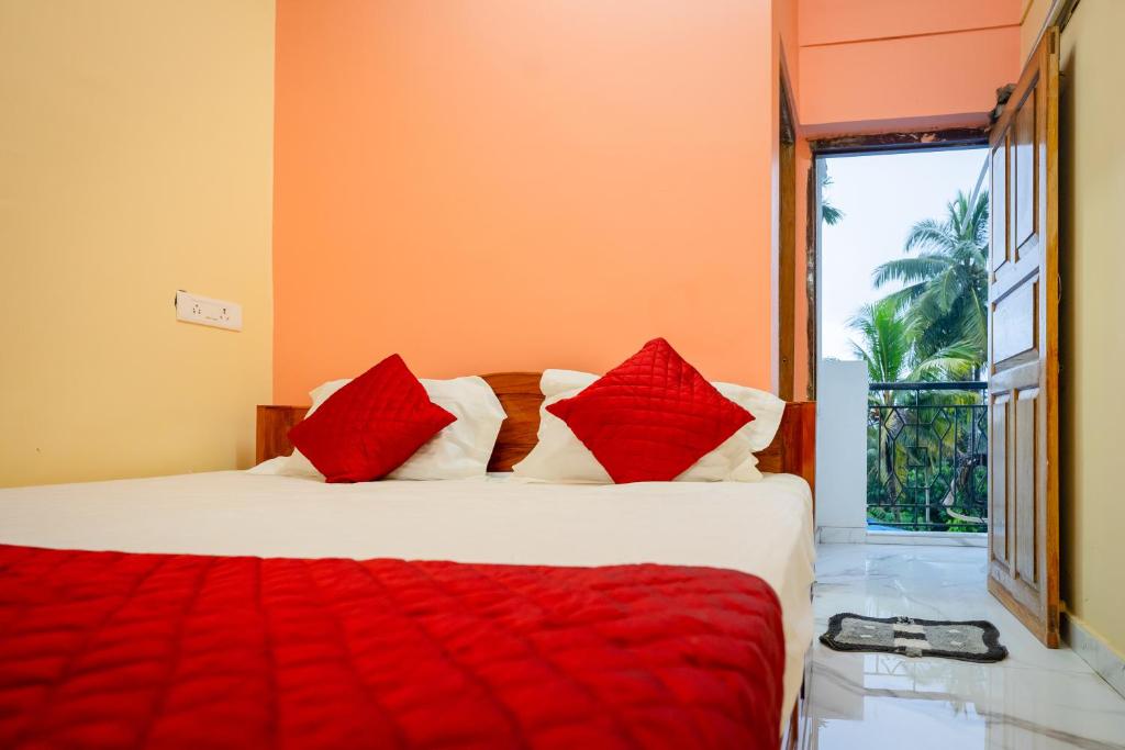 Schlafzimmer mit einem Bett mit roten Kissen und einem Fenster in der Unterkunft A&A BNB in Port Blair