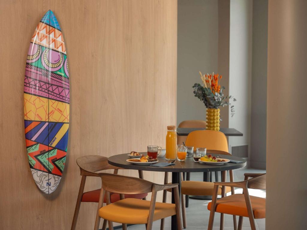 a dining room with a table and a surfboard on the wall at Novotel Paris Val de Fontenay in Fontenay-sous-Bois