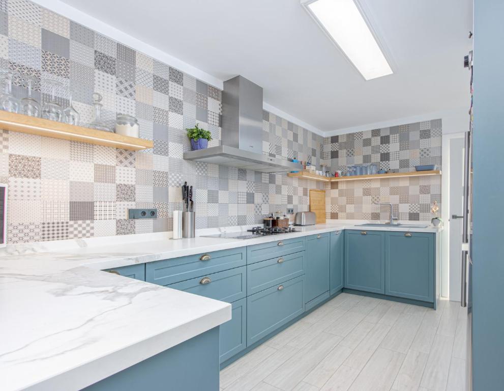 uma cozinha com armários azuis e azulejos na parede em Dalí City Apartamento em Figueres