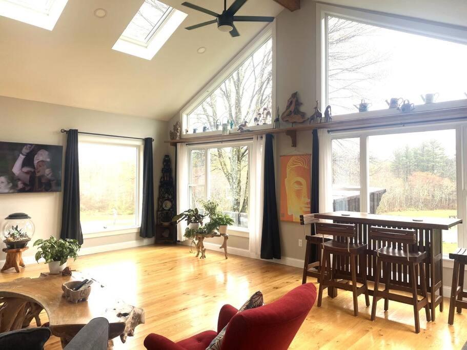 ein Wohnzimmer mit einem Tisch, Stühlen und Fenstern in der Unterkunft Zen Designed Guest Suite with PRIVATE 2-mile Trail Loop in Uxbridge